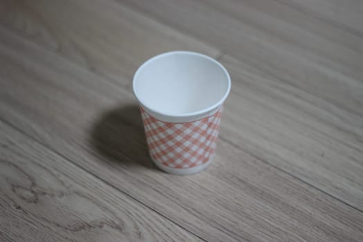 Paper, cardboard disposable glass on a wooden floor. Disposable paper cups on the wooden floor