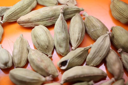 Closeup top view of dried green Elettaria cardamomum fruits with seeds, cardamom spice scattered on white background
