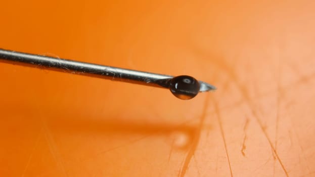 Close-up of vaccine drop on syringe needle. Water drop falling from the syringe needle