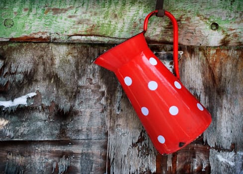 Vintage red jug hanging on rustic wooden wall