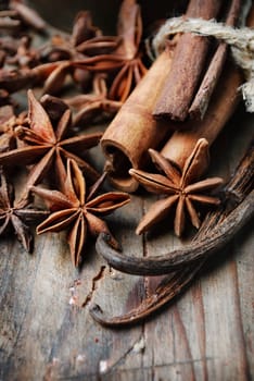 Anise seed, cinnamon and vanilla on grunge wooden plank