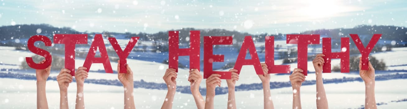 People Hands Holding Colorful English Word Stay Healthy. Snowy Winter Background With Snowflakes