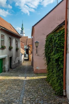 Narrow picturesque street with colorful buildings in historic center in medieval city Trebic, aisle in renaissance and baroque historical buildings at jewish quarter. Czech Republic