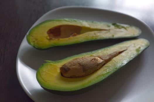 Avocado split in half, isolated on a black background