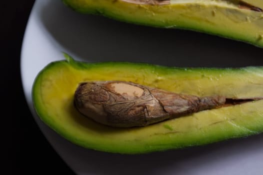Avocado split in half, isolated on a black background