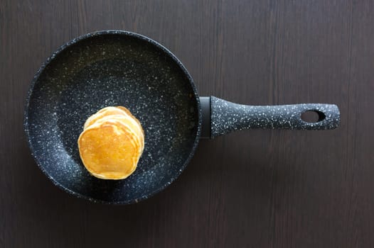 A pancakes in a frying pan on black background