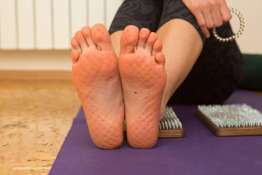 practice of standing on nails. Close-up of a yoga man standing on a sadhu board with sharp nails. Wooden sadhu board with nails for sadhu practice