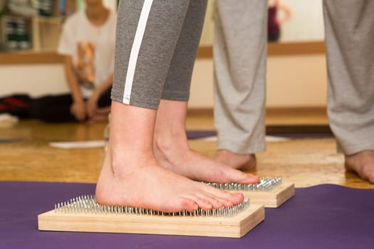 practice of standing on nails. Close-up of a yoga man standing on a sadhu board with sharp nails. Wooden sadhu board with nails for sadhu practice