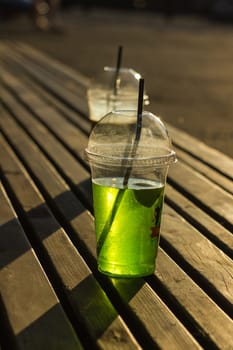 Bright soft drink in a transparent plastic cup.
