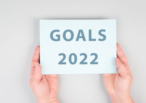 Goals 2022 is standing on a paper, hands are hold in the message, planning new achievements for the new year