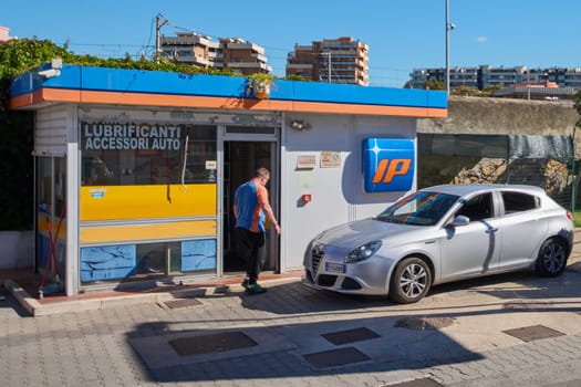 Civitavecchia. Italia - December 27, 2024: Exterior of IP gas station with a white car and urban background Concept: Fuel services, transportation and urban convenience in a travel friendly environment