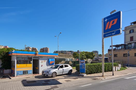 Civitavecchia, Italia - December 27, 2024: A gas station with modern design, a parked car, and a city backdrop on a sunny day. Concept: Urban infrastructure and transportation services.