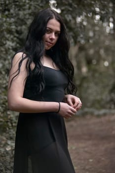 A brunette young Girl In A Black Dress alone In The Forest
