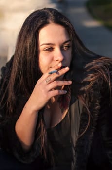 Schoolgirl teenager smokes outdoor on brick wall background. Smoking is harmful to our health