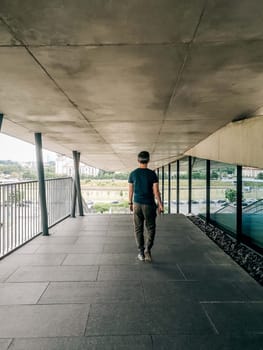 A man walks down the outer corridor of the building