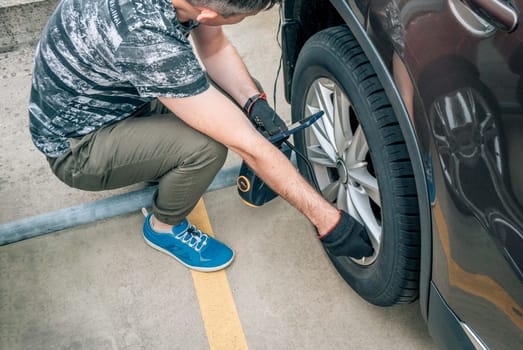 The man sat down near the car and rocks the wheel