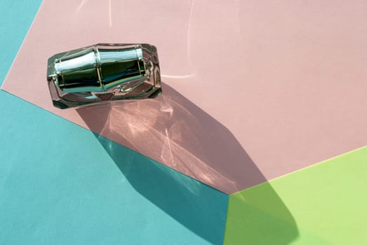 The shadow of a bottle of perfume in bright sunlight on a multi-colored background. Copy space