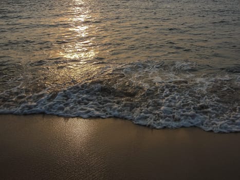 Reflection of the setting sun in the sea waves on the shore. Background. Copy space, travel photo