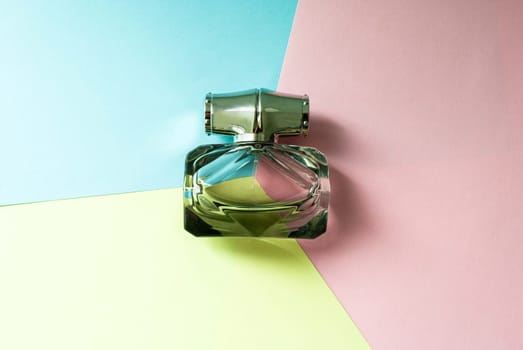 A bottle of eau de toilette on a multi-colored background. Copy space