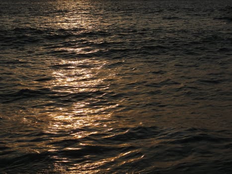 Background texture of sea water at sunset, reflection, light, waves, copy space, summer photo background