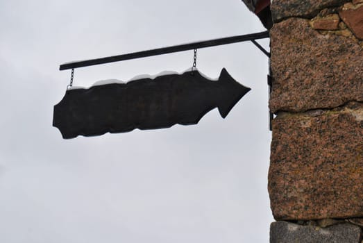 An old-style pointer hangs on the wall of the building against the sky, free space for text