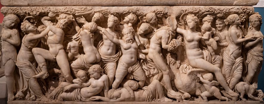 front view panoramic detail of stone statues basorelief scene on ancient sarcophagus in Antalya archeological museum