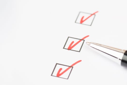 Red colored checkmarks in little black boxes, white paper, education, test, to do list, busniss concept