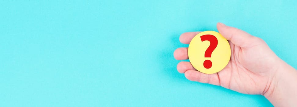 Woman holds a red question mark in her hand, blue background, copy space for text, finding answers
