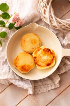 Cottage cheese pancakes, syrniki, curd fritters. Syrniki in small white pan. Top view. Homemade food, vertical image