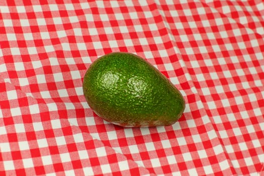 Whole avocado on red checkered tablecloth