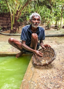 Galle, Sri Lanka - April 14, 2017: Local man standing next to hole full of water showing tourists how moonstones (semi precious gems) are gathered in moonstone mine.