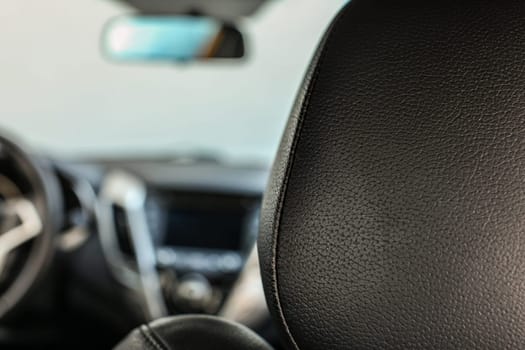 Detail closeup photo - leather on back of passenger seat, with blurred dashboard in background.