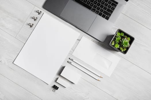 Blank branding stationery set and laptop on wooden background. Corporate identity mockup. Flat lay.