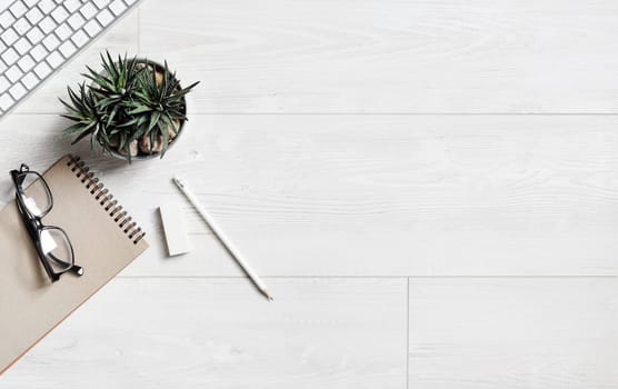 Wooden background with stationery. Overhead above view photo of notebook, succulent plant, glasses, pencil, eraser and keyboard. Copy space for your text. Flat lay.