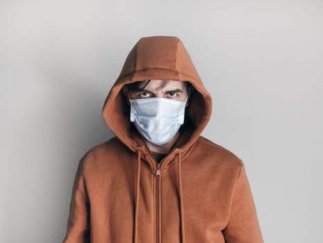 Man in a medical mask and brown hoodie. Stay at home. Virus protection.