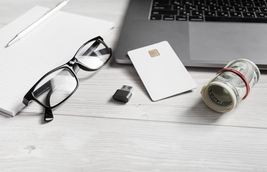 Online shopping and paying concept. Dollars, credit card, glasses, flash drive and laptop keyboard.