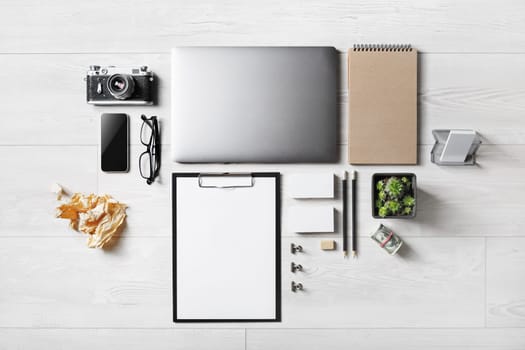 Set of office supplies with blank stationery and gadgets on wooden background. Flat lay.