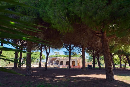 Remnants of ancient roman baths in Civitavecchia, Italy, partially obscured by trees. Great for historical content and nature photography.