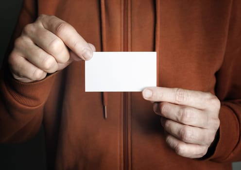 Man holding and showing blank white business card.