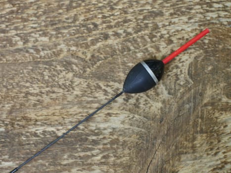large black fishing bobber with red antenna long keel, still life