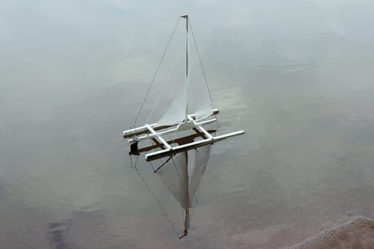 catamaran sails blown by the wind reflected in the water