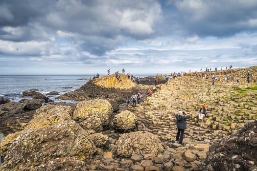 Bushmills, Northern Ireland, Aug 2019 Tourists sightseeing hexagonal rock formation in Giants Causeway, Wild Atlantic Way and UNESCO world heritage