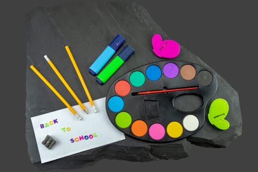 Closeup of colorful school supplies with copy space on blackboard background. Back to school written with colorful letters on blackboard. Concept education.