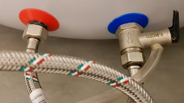 Connection of water supply, hot and cold water to the boiler. Hose for hot and cold water in the bathroom. Plumbing connections for a domestic electric water heater