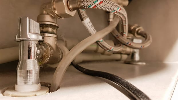 Connection of water supply, hot and cold water to the boiler. Hose for hot and cold water in the bathroom. Plumbing connections for a domestic electric water heater