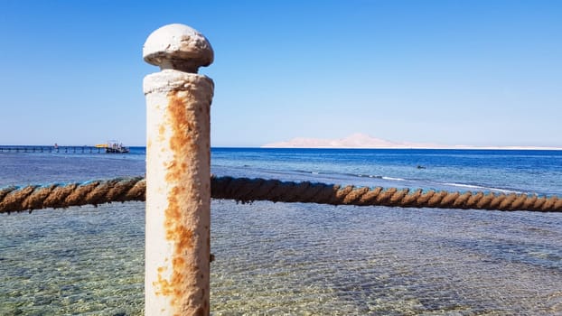 Long pontoon on the Red Sea in Egypt. Pontoon for descent into the water. Wooden bridge on the territory of the Amway Hotel in Sharm El Sheikh with metal fences and a rope over the sea with waves.