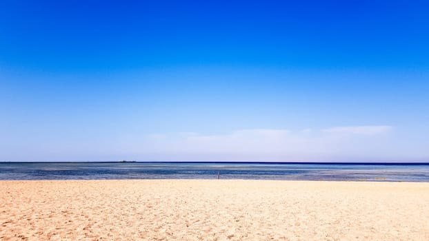 A beautiful sandy beach without people and a tropical blue sea with blue sky background