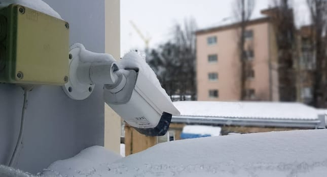 Large white surveillance camera over a window against the backdrop of a public building. close-up. CCTV camera installed on the outer window of the house