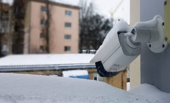 Large white surveillance camera over a window against the backdrop of a public building. close-up. CCTV camera installed on the outer window of the house