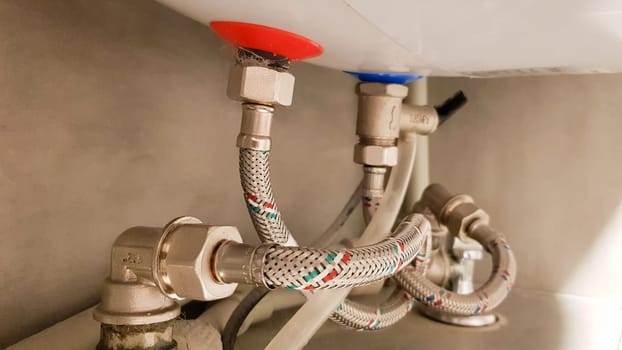 Connection of water supply, hot and cold water to the boiler. Hose for hot and cold water in the bathroom. Plumbing connections for a domestic electric water heater